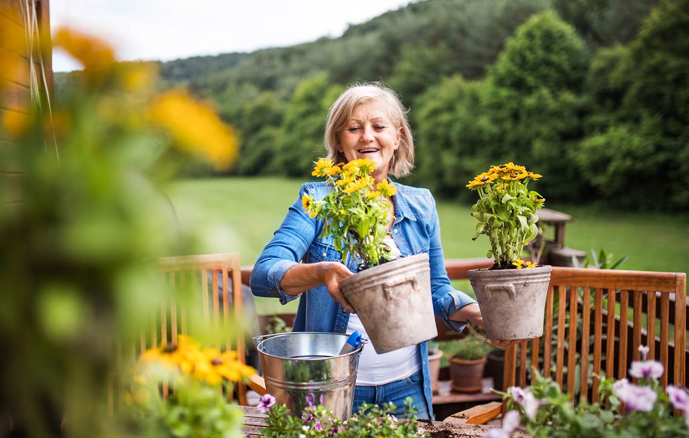 ältere Dame bepflanzt Blumentöpfe auf Ihrer Terrasse